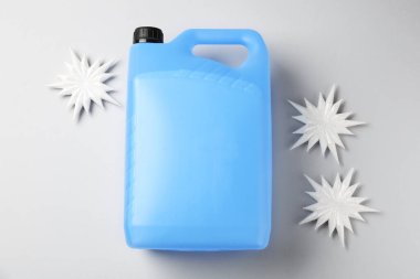 Plastik kapta antifriz ve gri arka planda dekoratif kar taneleri, düz yatıyordu.
