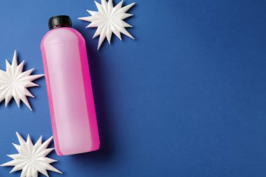 Plastik şişede antifriz ve mavi arka planda dekoratif kar taneleri. Metin için boşluk