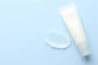 Açık mavi arka planda nemlendirici dudak kremi ve tüp, üst manzara. Metin için boşluk