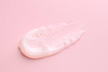 Pembe arka planda nemlendirici dudak kremi, yakın plan.