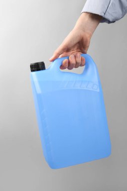 Açık gri arka planda antifriz kutusu olan kadın, yakın plan.