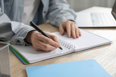 İçerideki ahşap masada notlar alan bir kadın, yakın plan. Kendi kendine çalışma.