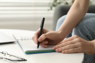 İçerideki beyaz masada notlar alan bir kadın, yakın plan. Kendi kendine çalışma.