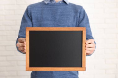 Kapalı alanda boş küçük tahta tutan adam, yakın plan.
