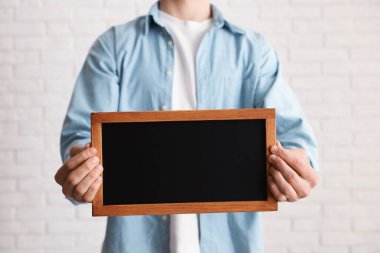 Kapalı alanda boş küçük tahta tutan adam, yakın plan.
