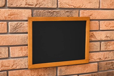 Tuğla duvarda boş küçük bir tahta.