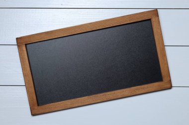 Beyaz ahşap zemin üzerinde boş küçük karatahta, üst görünüm