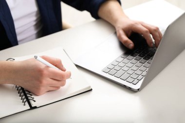 İçerideki masada ders sırasında not alan bir adam, yakın plan. Kendi kendine çalışma.