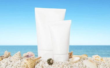 Okyanus kıyısındaki sahilde güneş kremi ürünleri ve deniz kabukları.