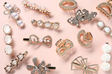 Soluk pembe arka planda farklı saç tokaları, düz yatış.