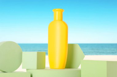 Okyanus kıyısındaki sahilde bir şişe güneş kremi. Podyumlu şık bir sunum