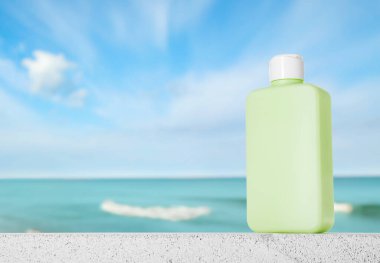 Okyanus kıyısındaki sahilde bir şişe güneş kremi.