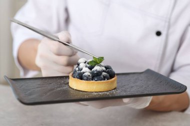 Şekerci, mutfaktaki gri masada nane şekerli tart hazırlıyor, yakın plan.