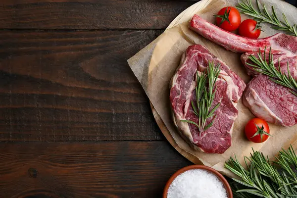 Çiğ sığır eti, biberiye, domates ve ahşap masa üzerinde tuz, düz yatak. Metin için boşluk