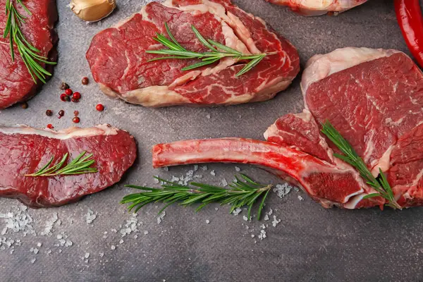 Kahverengi desenli masaya çiğ et, tuz ve biberiye parçaları serpiştirilmiş.