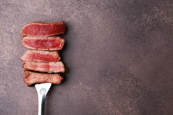 Lezzetli dilimlenmiş sığır filetosu. Kahverengi desenli masa, üst manzara. Metin için boşluk