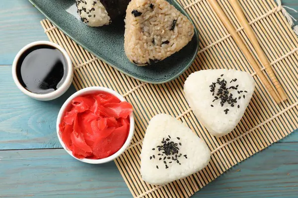 Pirinç topları (onigiri) açık mavi ahşap masa üzerinde servis edilir. Geleneksel Japon yemeği