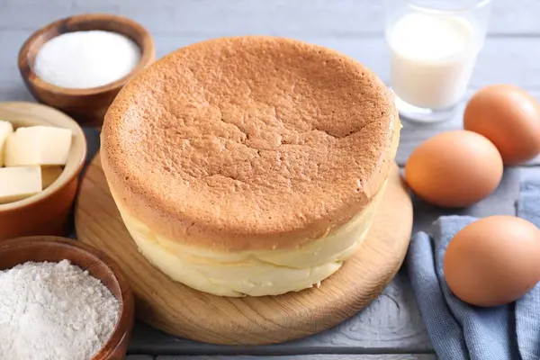 Tasty Japanese Castella sponge cake and ingredients on grey wooden table, closeup