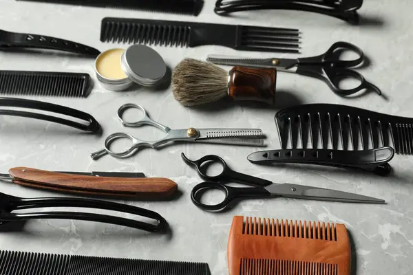 Açık gri masada birçok farklı berber aletleri var.