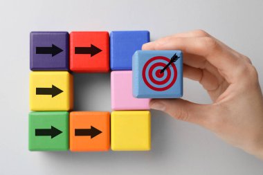 Hedef alınıyor. Kadın arkaplanda okları olan diğer kadınların yanına küpü yerleştiriyor.