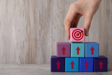 Hedef alınıyor. Bir kadın tahtaya okları olan diğer kadınların piramidinin tepesine küpü yerleştiriyor, yakın plan.