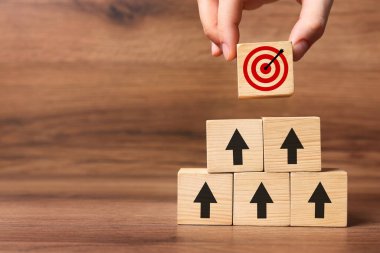 Hedef alınıyor. Bir kadın tahtaya okları olan diğer kadınların piramidinin tepesine küpü yerleştiriyor, yakın plan.