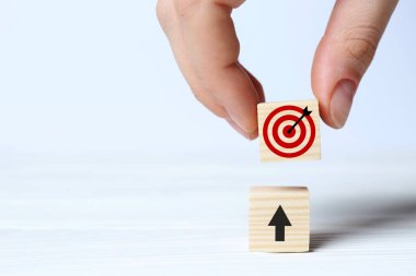 Hedef alınıyor. Bir kadın diğerinin üstüne küpü yerleştiriyor. Arkaplanda ok var. Yakın plan.