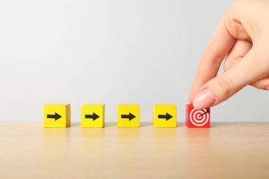 Hedef alınıyor. Tahta masaya okları olan diğer kadınlara gözleriyle küp koyan bir kadın.