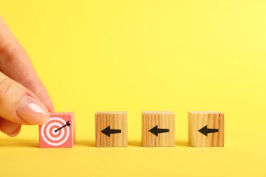 Hedef alınıyor. Kadın, sarı arka planda okları olanlara hedef tahtası koyuyor, yakın plan.