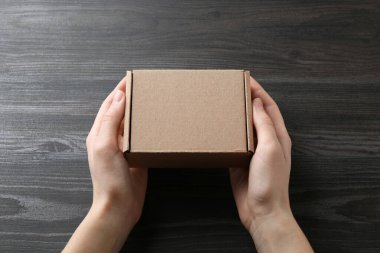 Karanlık ahşap arka planda boş karton kutulu bir kadın, yakın plan. Tasarım için model