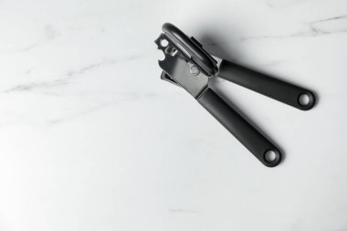 Beyaz mermer masada bir konserve açacağı, üst manzara. Metin için boşluk