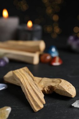 Palo santo sopaları, değerli taşlar ve siyah masada yanan mumlar bulanık ışıklara karşı, yakın çekim