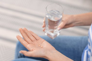 Doğum kontrol hapları ve bir bardak suyu olan kadın, yakın plan.