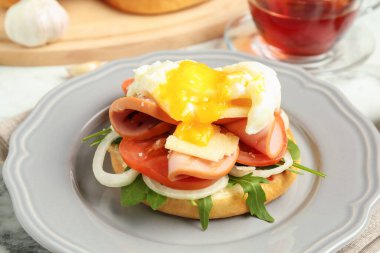 Lezzetli bir kahvaltı. Haşlanmış yumurta, jambon, domates, roka ve ekmek beyaz mermer masada, yakın plan.