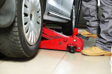 Benzin istasyonunda makas kriko ile otomobil kaldırma, yakın çekim