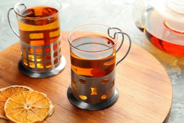 Gri desenli masada servis edilen metal tutacaklı çay bardakları.