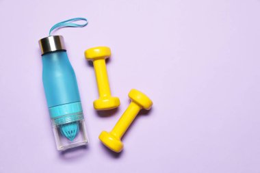 Dambıllar ve su şişesi menekşe arka planda, düz yerde. Metin için boşluk