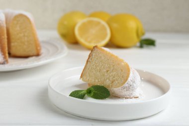 Lezzetli limonlu kek, pudra şekerli ve nane şekerli, beyaz ahşap masa, yakın plan.