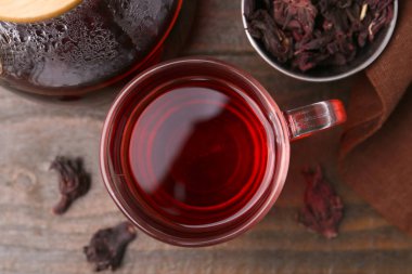 Cam fincanda leziz amber çayı, çaydanlık ve kuru roselle sepals ahşap masada, düz uzanmış