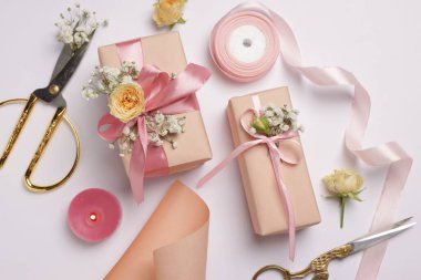 Çiçekçi. Beyaz arkaplanda kutular, çiçekler, makas ve kurdele, düz konum