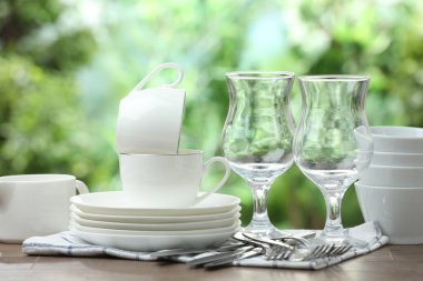 Clean dishware on wooden table against blurred background