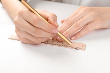 Masada cetvel ve kalemle çizim yapan kadın, yakın plan.