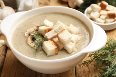 Lezzetli mantar kremalı çorba, kızarmış ekmek, dereotu ve ahşap masa malzemeleri, yakın plan.