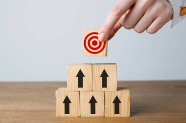 Hedef alınıyor. Bir kadın tahtaya okları olan diğer kadınların piramidinin tepesine küpü yerleştiriyor, yakın plan.