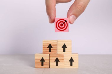 Hedef alınıyor. Masasında okları olan diğer kadınların piramidinin tepesine pembe küpü koyan kadın, yakın plan.