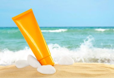 Okyanusun yakınındaki kumlu sahilde güneş kremi ve taş tüpü.