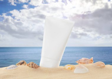 Deniz kenarındaki kumsalda güneş kremi ve deniz kabukları.
