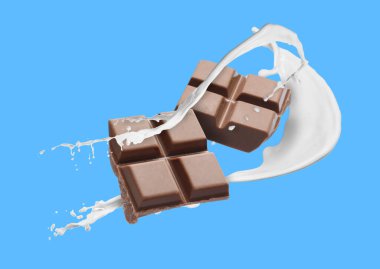 Nefis çikolata parçaları ve açık mavi arka planda havada sütün damlaları.