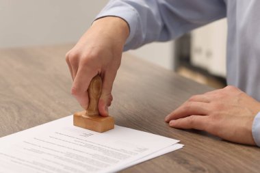 İçerideki ahşap masaya lisans belgesi yapıştıran adam, yakın plan.