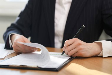 İçerideki ahşap masada, ruhsat sözleşmesi imzalayan kadın, yakın plan.